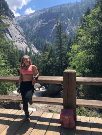 Natalia Aponte on a Bridge with trees and mountains in the background in Yosemite Valley